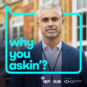 A photo of a person wearing a blue suit jacket and a white shirt, with a lanyard around their neck. They are standing outside in front of a building, looking at the camera. Around them is a bright blue speech bubble with text that reads, why you askin'?