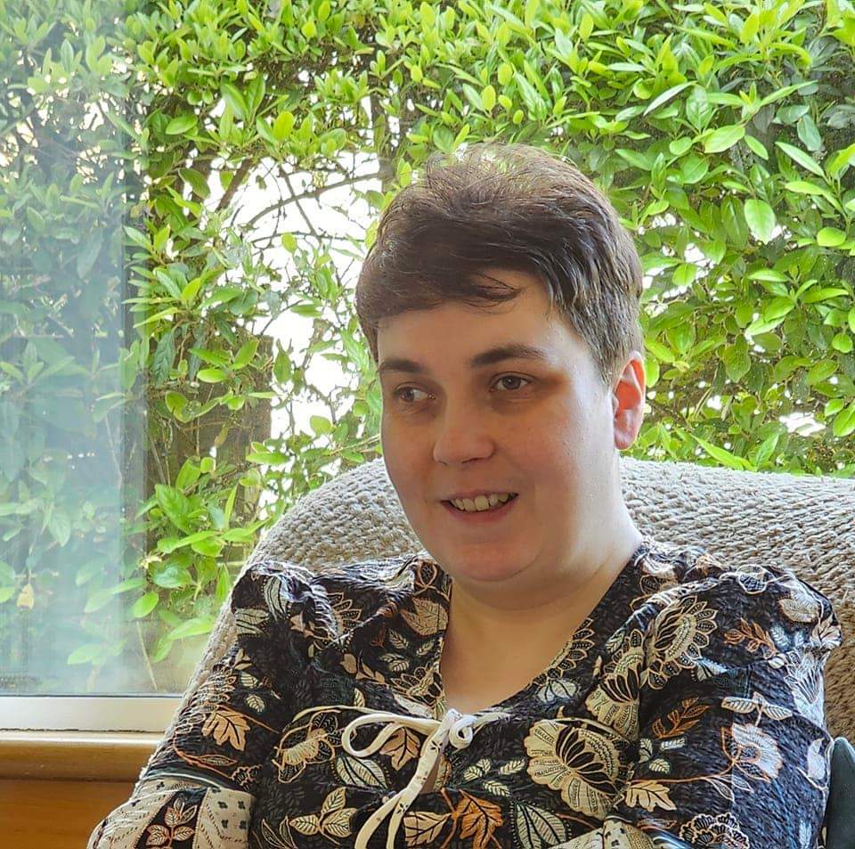 A head and shoulders image of a woman sat in a chair smiling.
