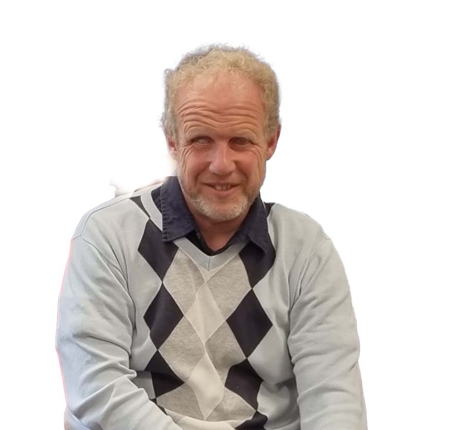 Photo of a man wearing a patterned jumper smiling.